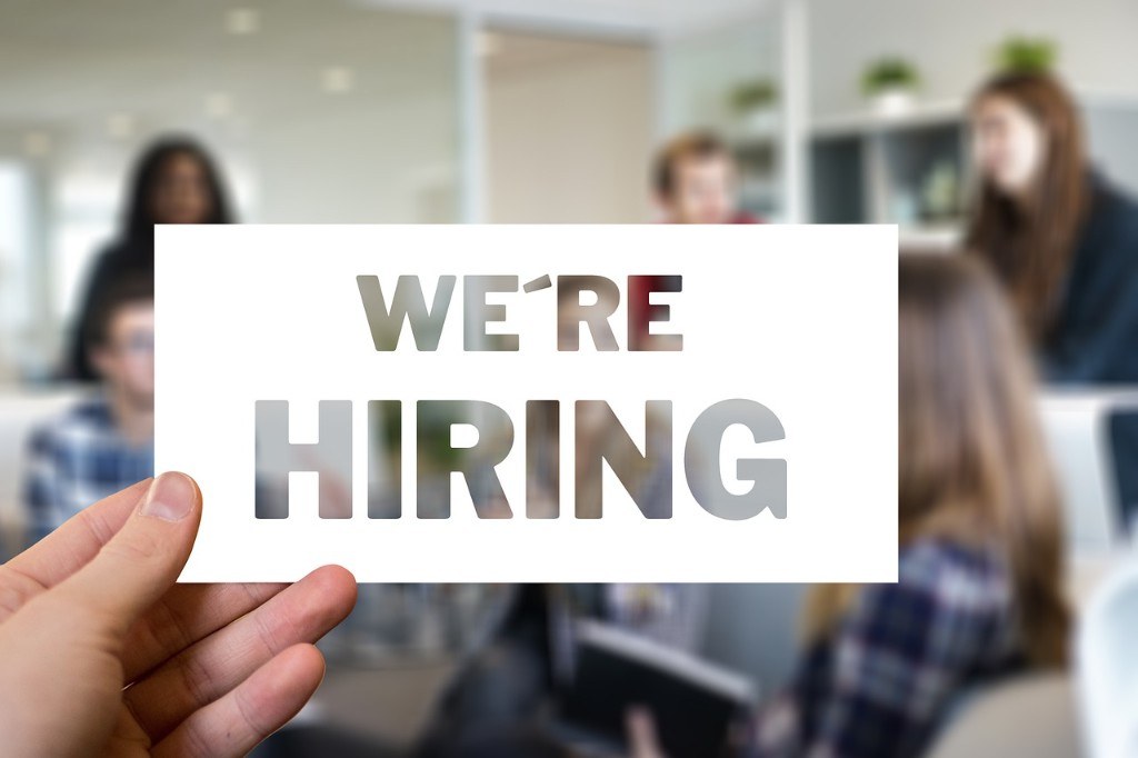 Hand holding a we are hiring sign in a modern office